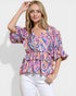 Woman wearing a colorful patterned top against a white background