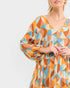 Woman wearing a colorful geometric patterned dress on a light gray background