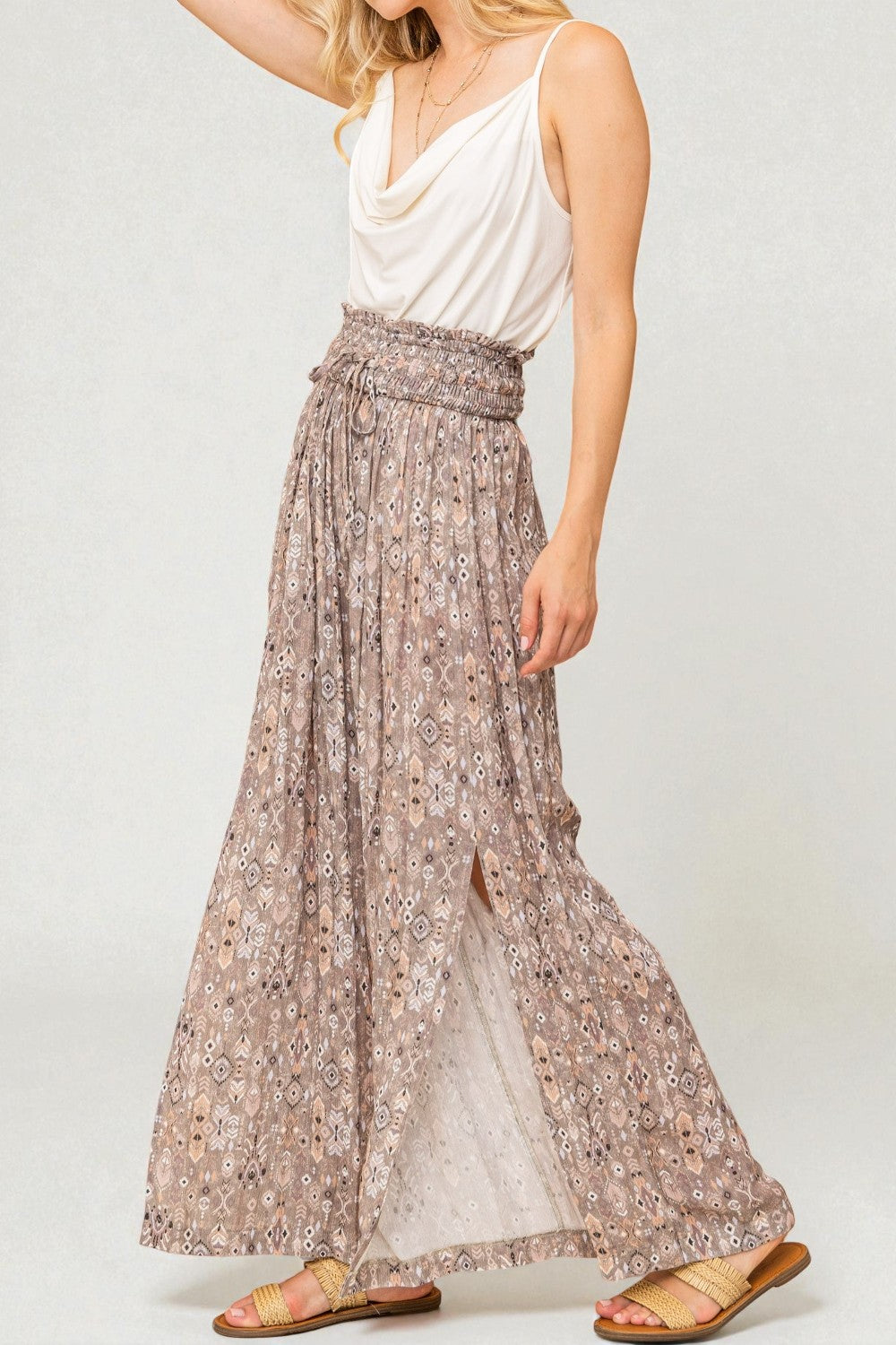 Woman wearing a white top and floral skirt on a plain background