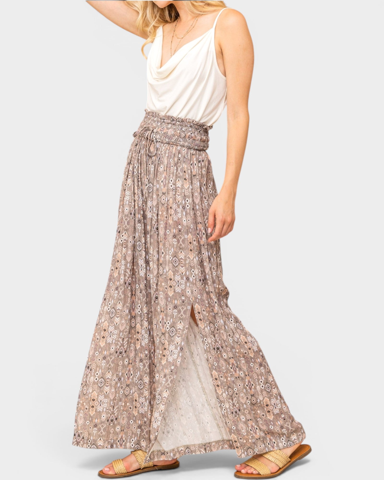 Woman wearing a long floral skirt and white top on a plain background