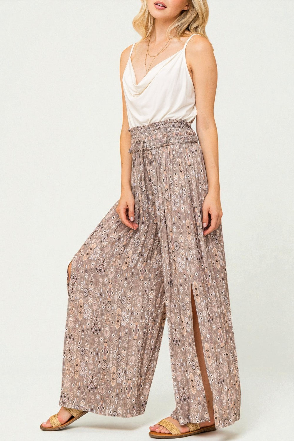 Woman wearing a white top and patterned wide-leg pants on a white background