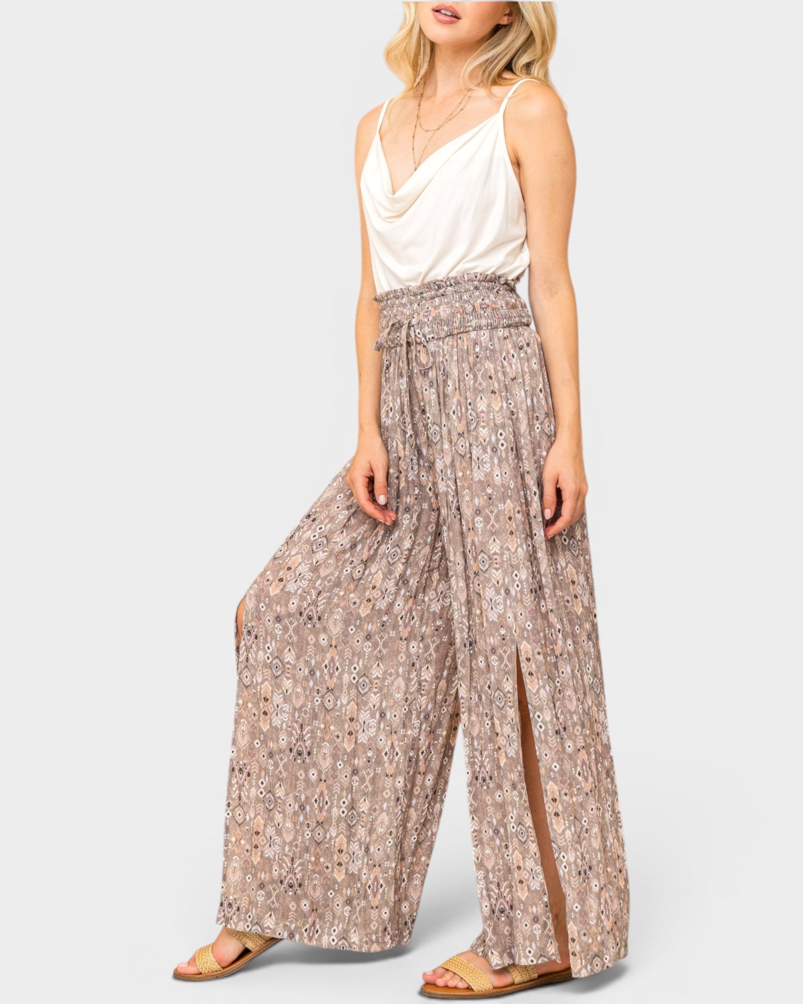 Woman wearing a white top and patterned wide-leg pants on a light gray background