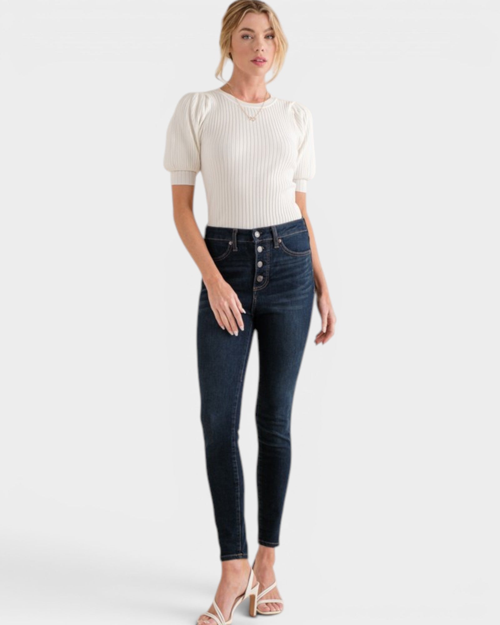 Woman wearing a white top and dark blue jeans on a white background