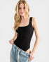 Woman wearing a black tank top and blue jeans on a white background