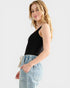 Woman wearing a black sleeveless top and light blue jeans on a white background