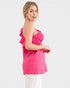 Woman wearing a pink ruffled top on a white background