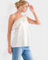 Woman wearing a white one-shoulder top and blue jeans on a plain background