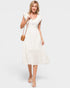 Woman wearing a white dress holding a brown handbag on a white background