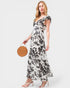Woman wearing a floral dress holding a round woven bag on a white background