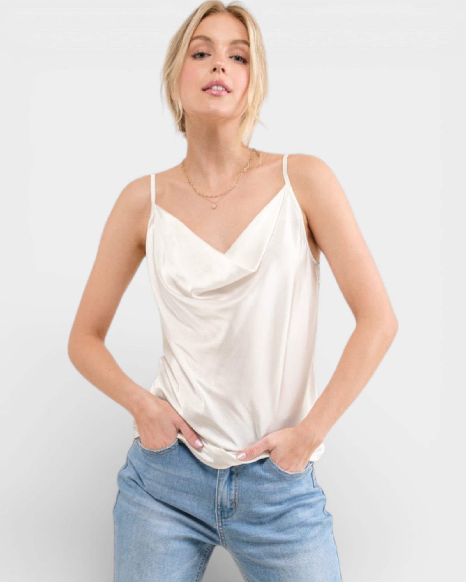Woman wearing a cream-colored tank top and light blue jeans on a white background