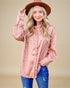 Woman wearing a pink leopard print shirt and blue jeans with a brown hat on a beige background