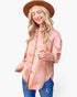 A woman wearing a dusty pink leopard-print button-up shirt, blue jeans, and a brown wide-brim hat, photographed against a solid white background.