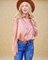 Woman wearing a pink leopard print shirt and blue jeans with a brown hat against a beige background