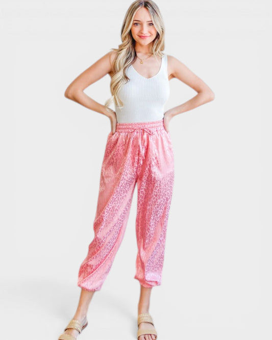 Woman wearing a white tank top and pink patterned pants on a white background