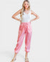 Woman wearing a white tank top and pink patterned pants on a white background