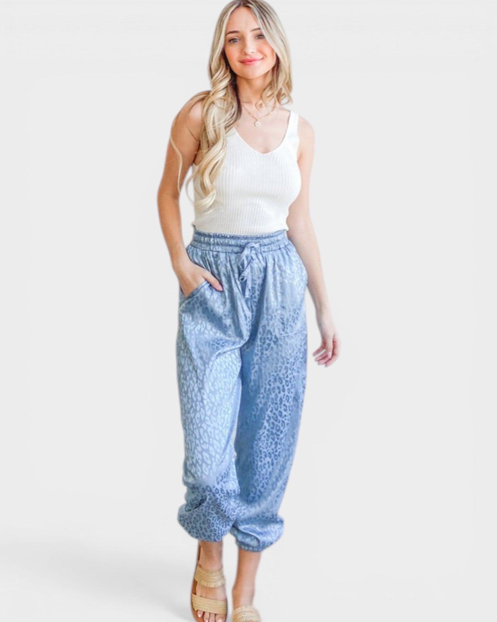 Woman wearing a white tank top and blue patterned pants on a white background