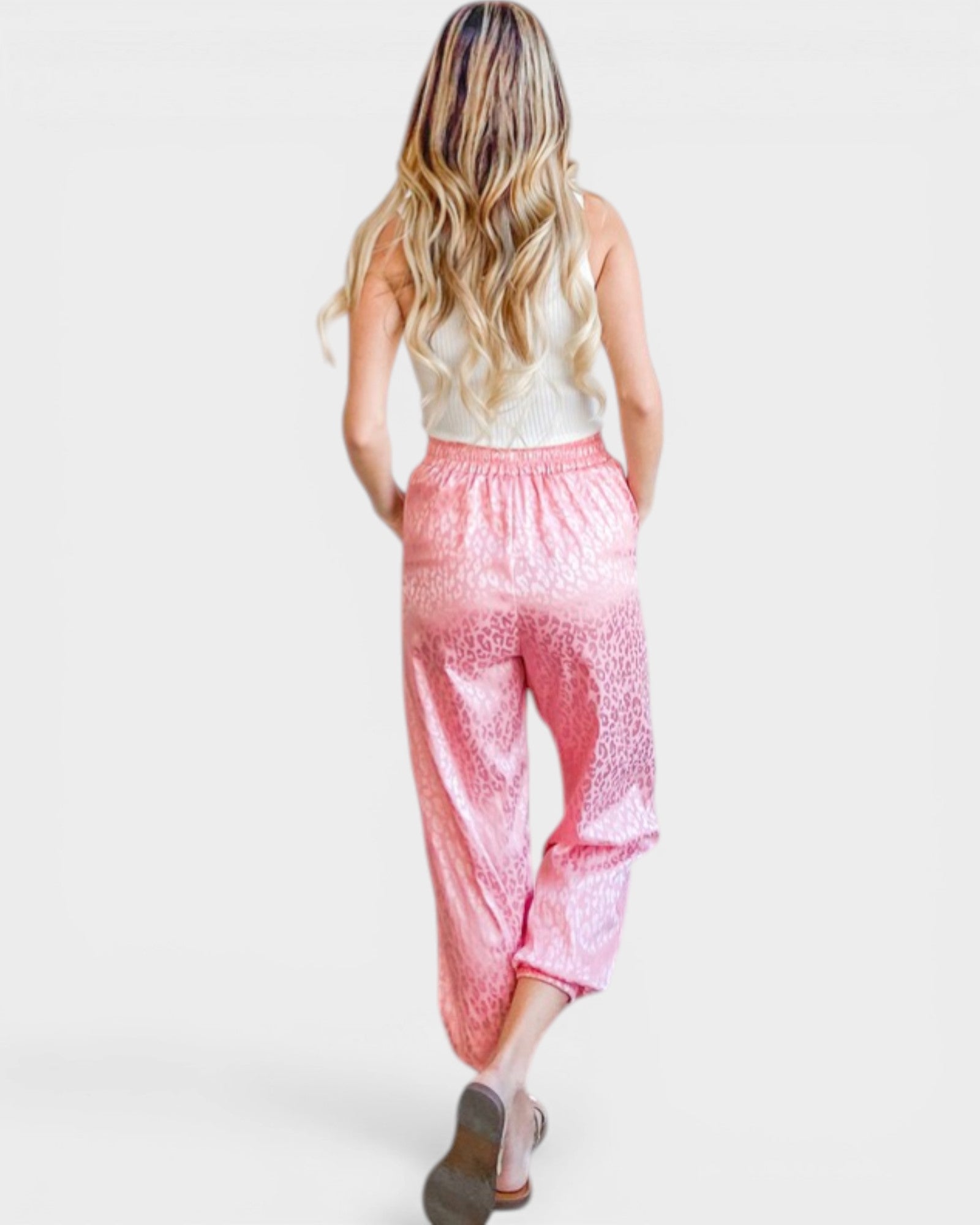 Woman wearing pink leopard print pants on a white background