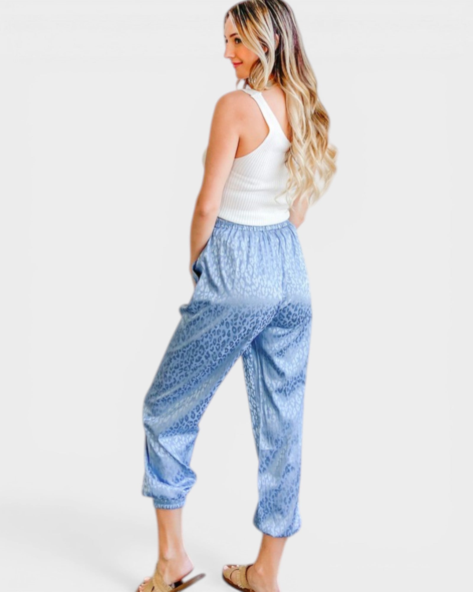 Woman wearing blue patterned pants and a white top on a white background