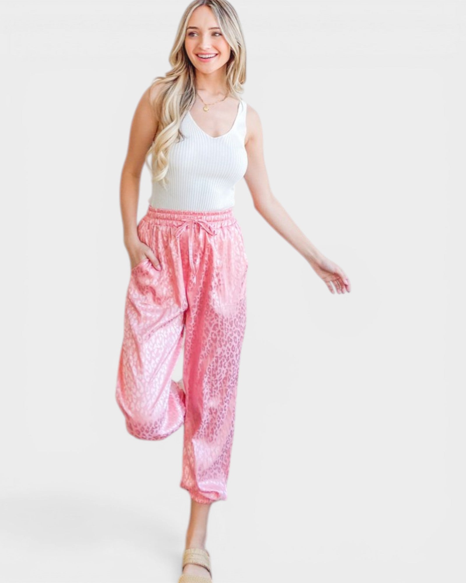 Woman wearing a white top and pink pants on a white background