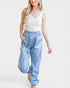 Woman wearing a white sleeveless top and blue patterned pants on a white background