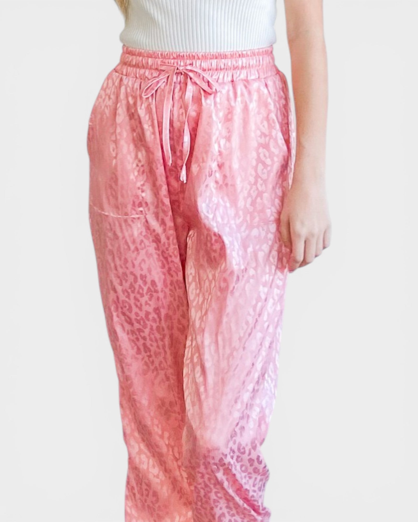 Pink leopard print pants worn by a person on a white background