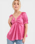 Woman wearing a pink patterned top with blue jeans on a white background