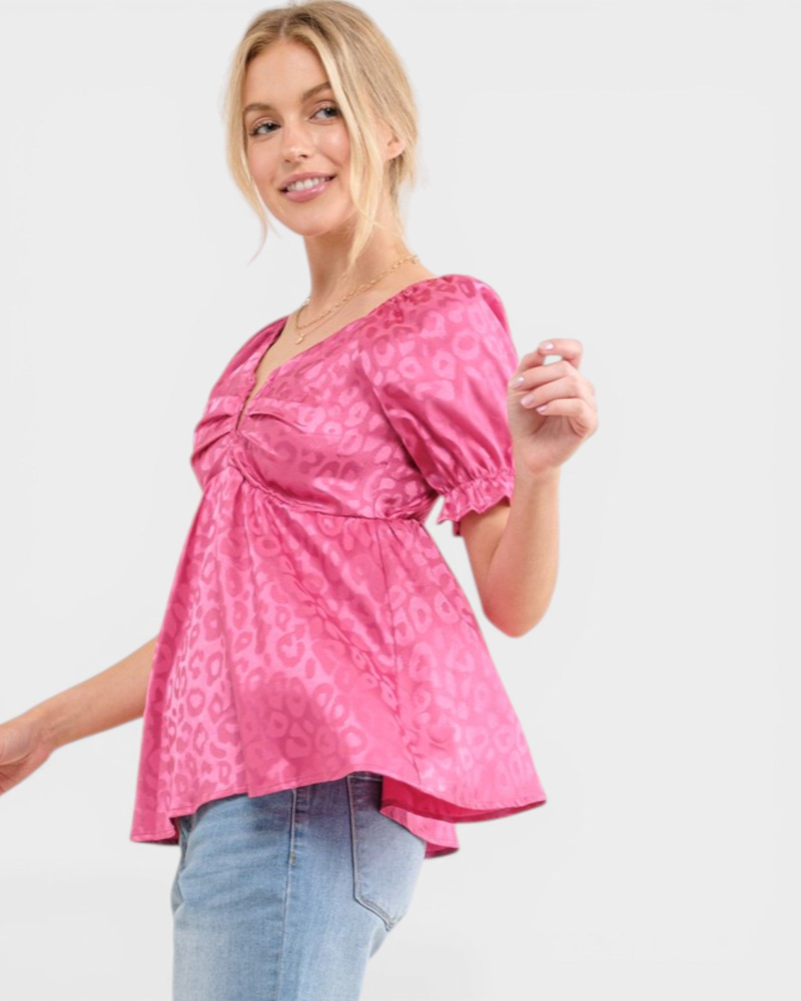 Woman wearing a pink patterned top and blue jeans on a white background