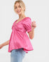 Woman wearing a pink patterned top and blue jeans on a white background