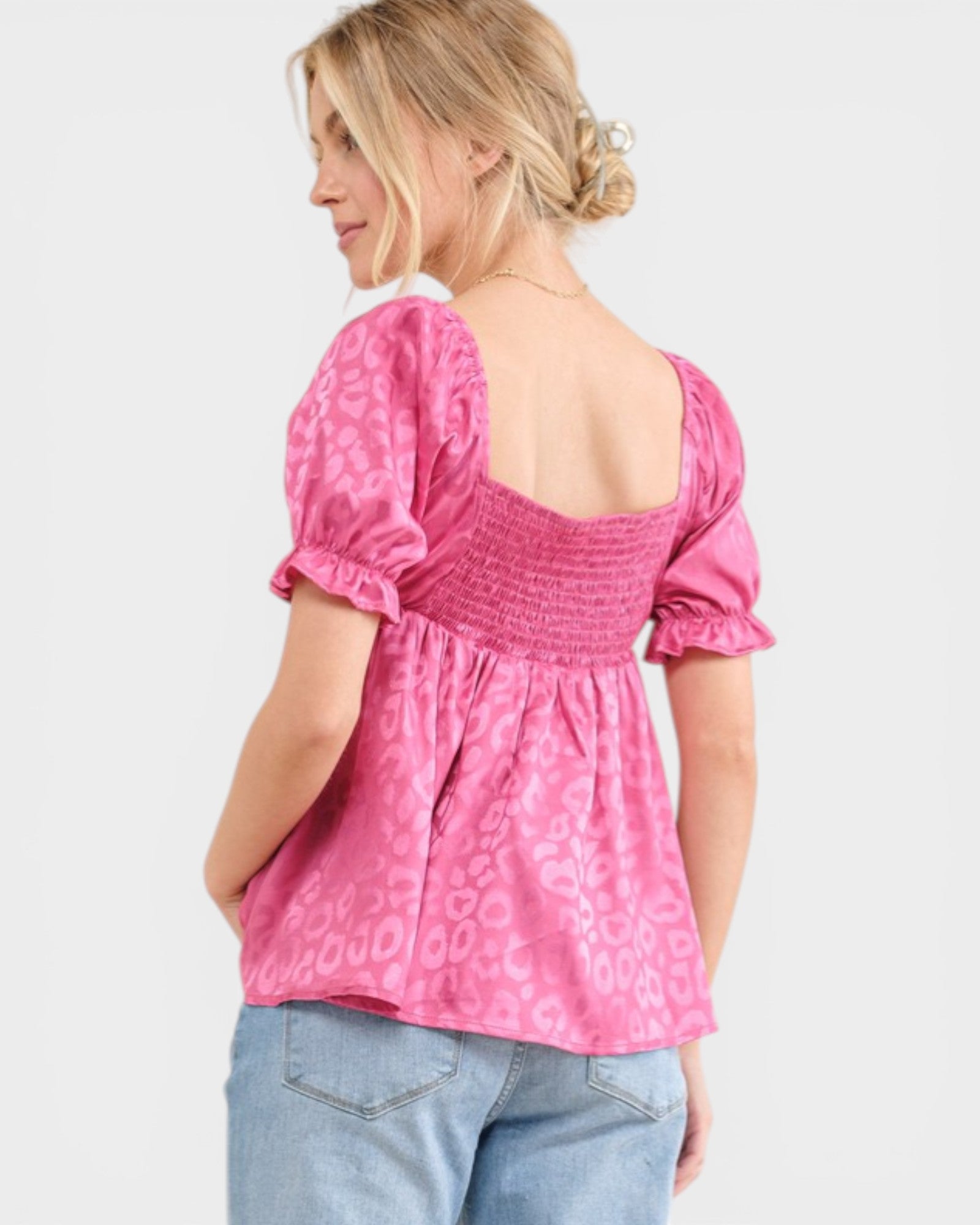 Woman wearing a pink blouse with puff sleeves on a white background