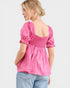 Woman wearing a pink blouse with puff sleeves on a white background
