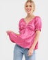 Woman wearing a pink satin top with puffed sleeves on a white background