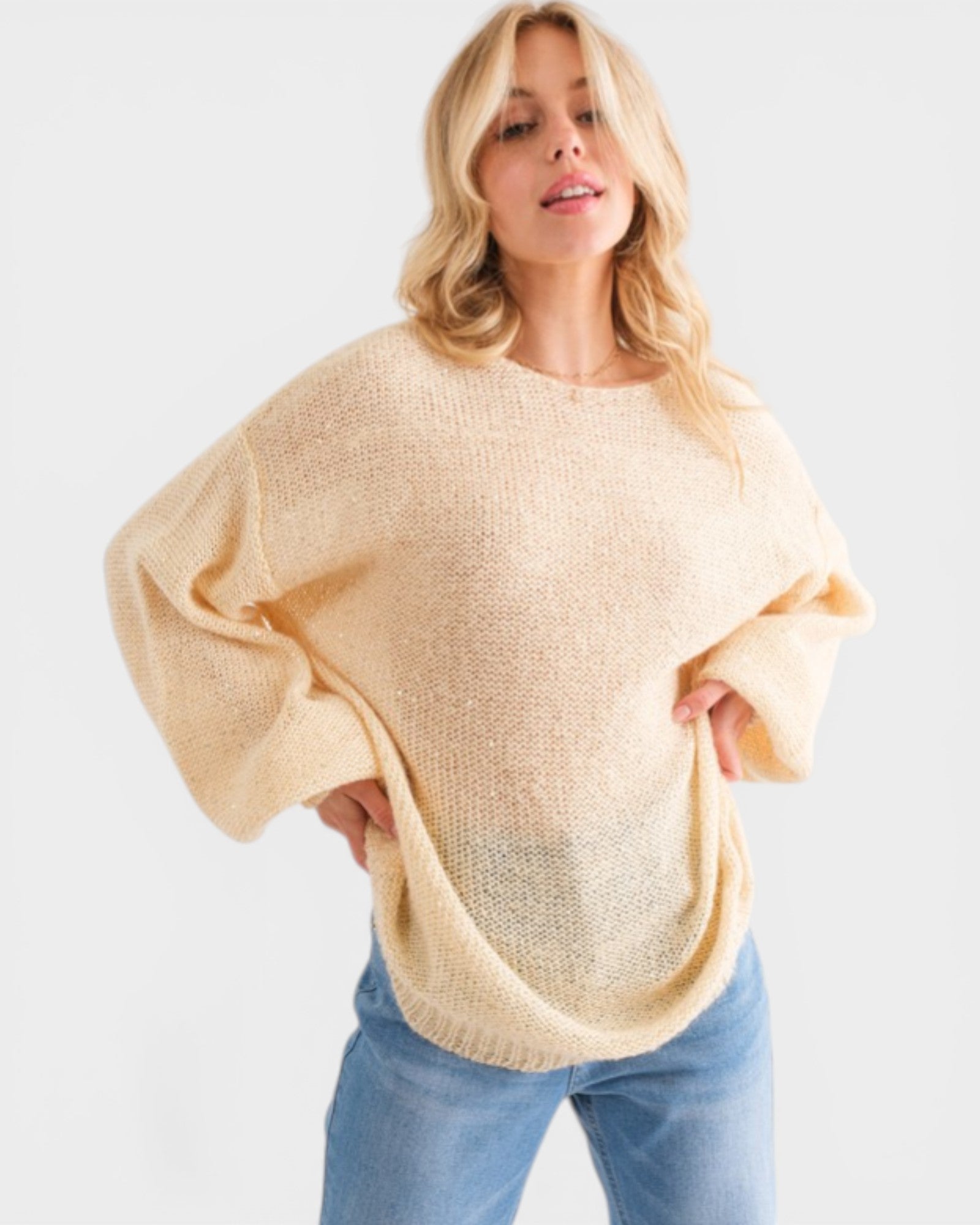 Woman wearing a beige sweater and blue jeans on a white background