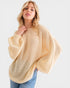 Woman wearing a beige poncho against a white background