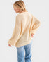 Person wearing a light yellow sweater and blue jeans on a white background