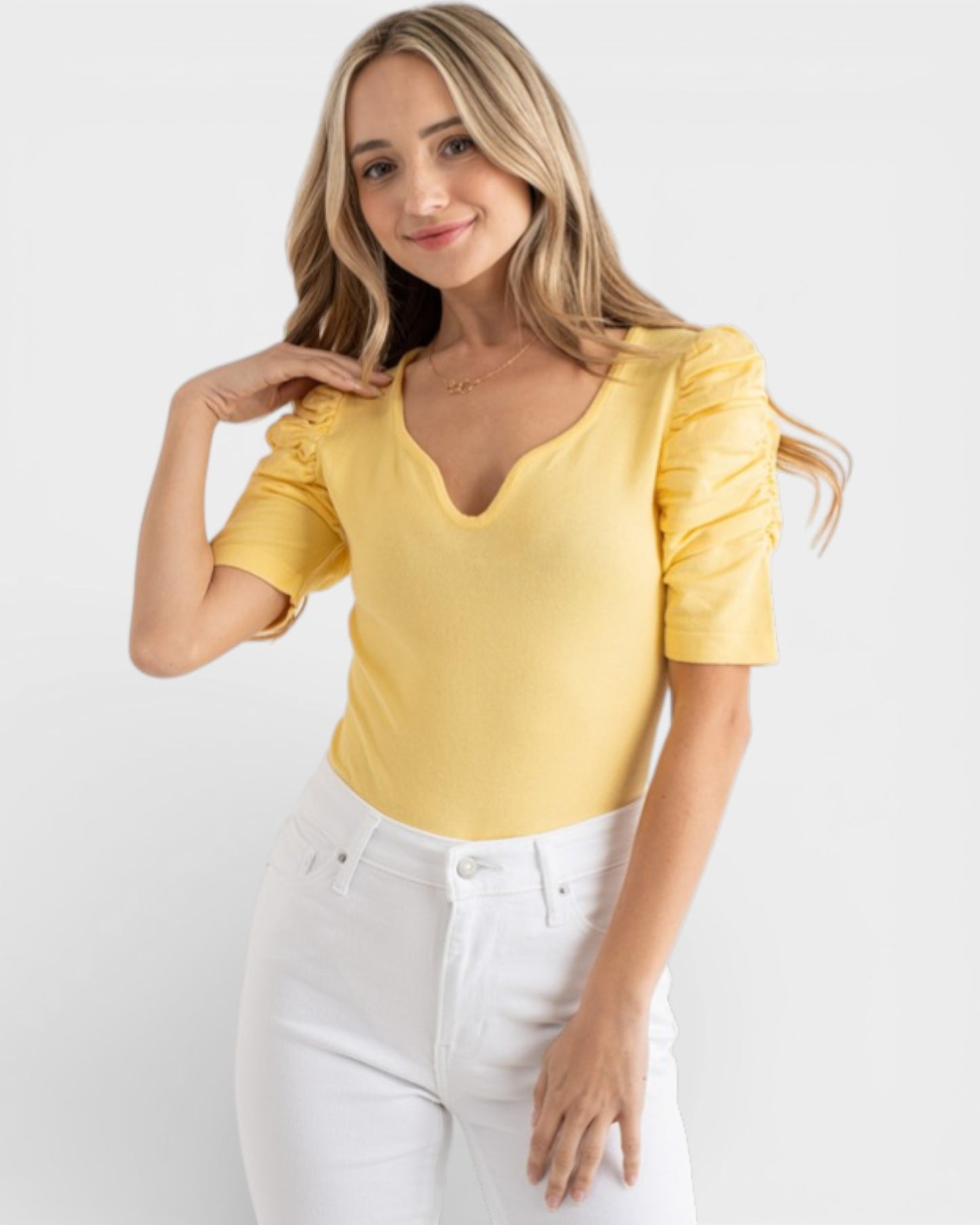 Woman wearing a yellow top with puff sleeves on a white background