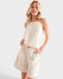 Woman wearing a beige sleeveless top and shorts on a white background
