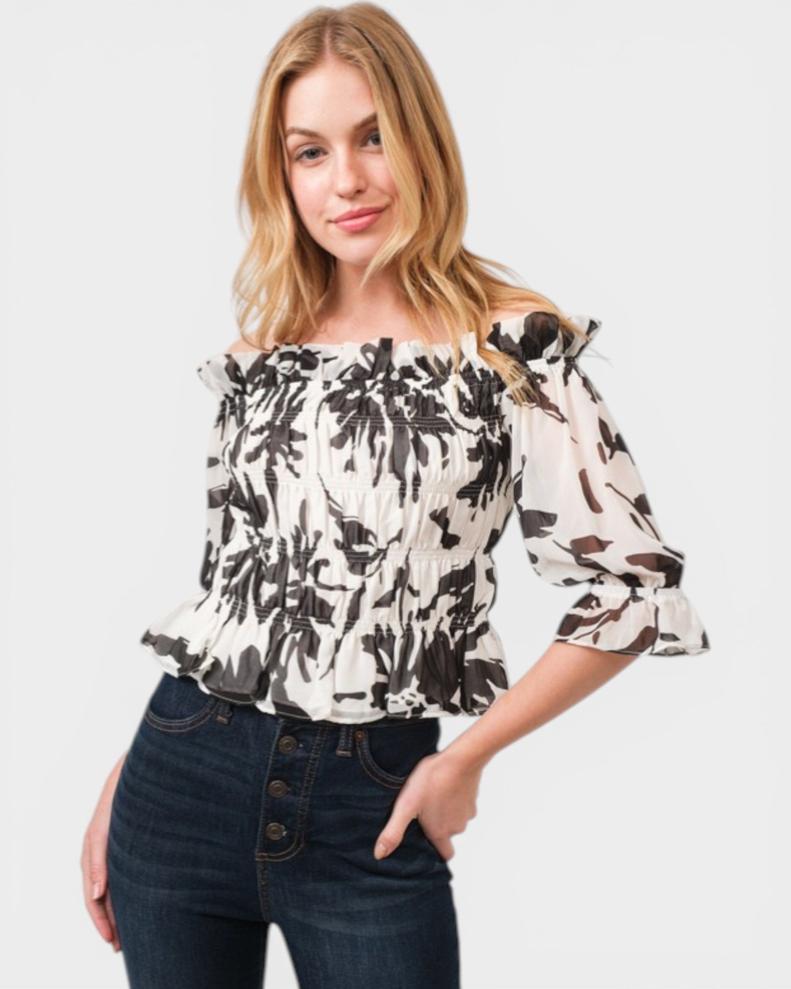 Woman wearing a floral off-shoulder top and jeans on a white background