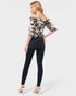 Woman wearing a floral blouse and dark jeans on a white background