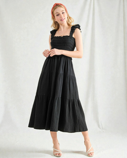 Woman wearing a black dress with ruffled straps against a white background