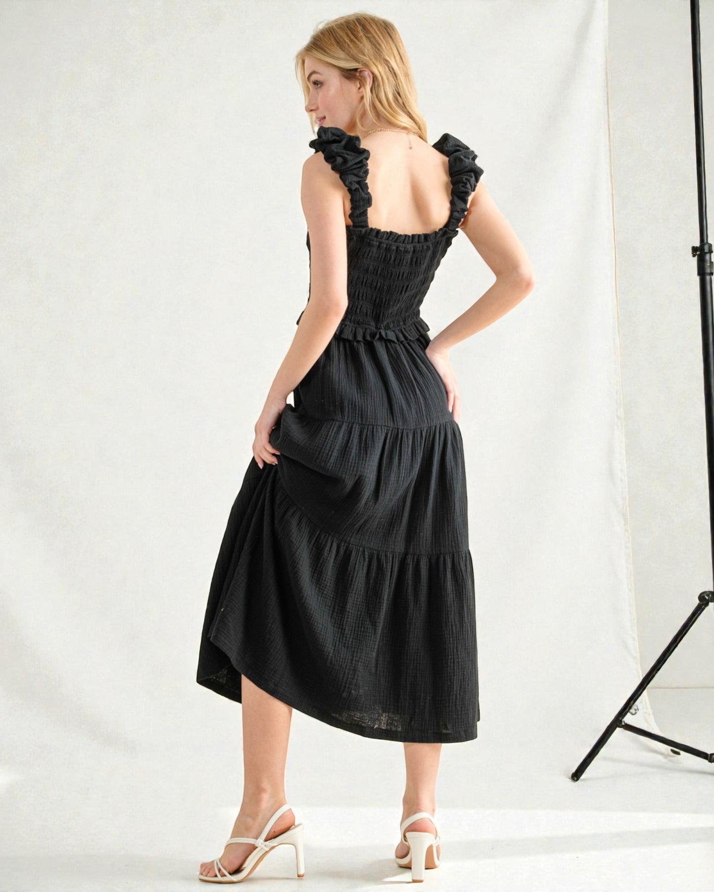 Woman wearing a black dress with ruffled straps against a white background