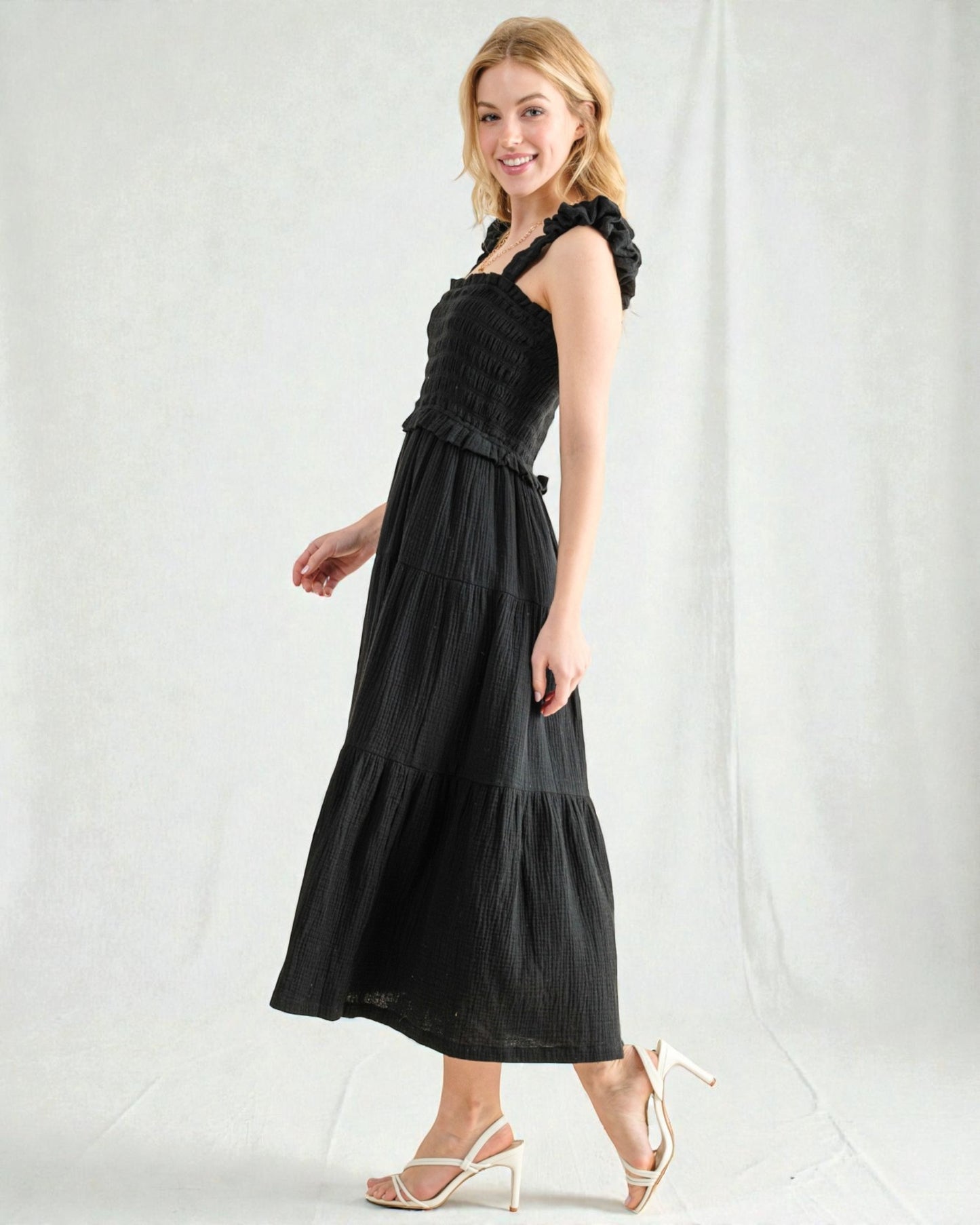 Woman wearing a black dress with ruffled top on a white background