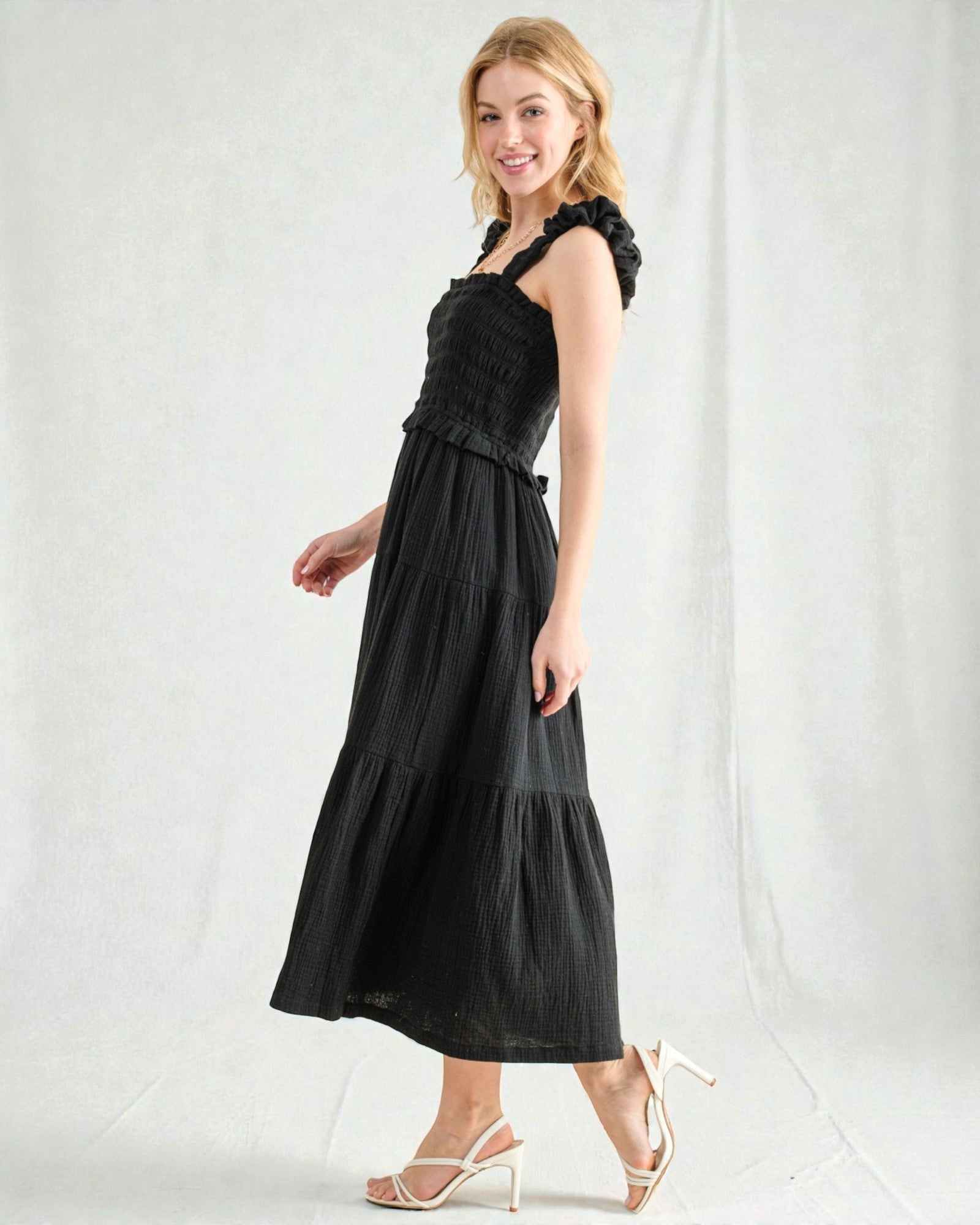 Woman wearing a black dress with ruffled top on a white background