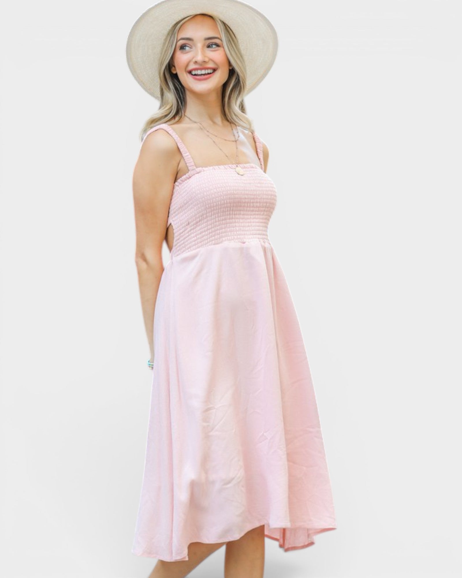 Woman wearing a light pink dress and beige hat against a white background