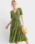 Woman wearing a green dress holding a woven bag on a white background