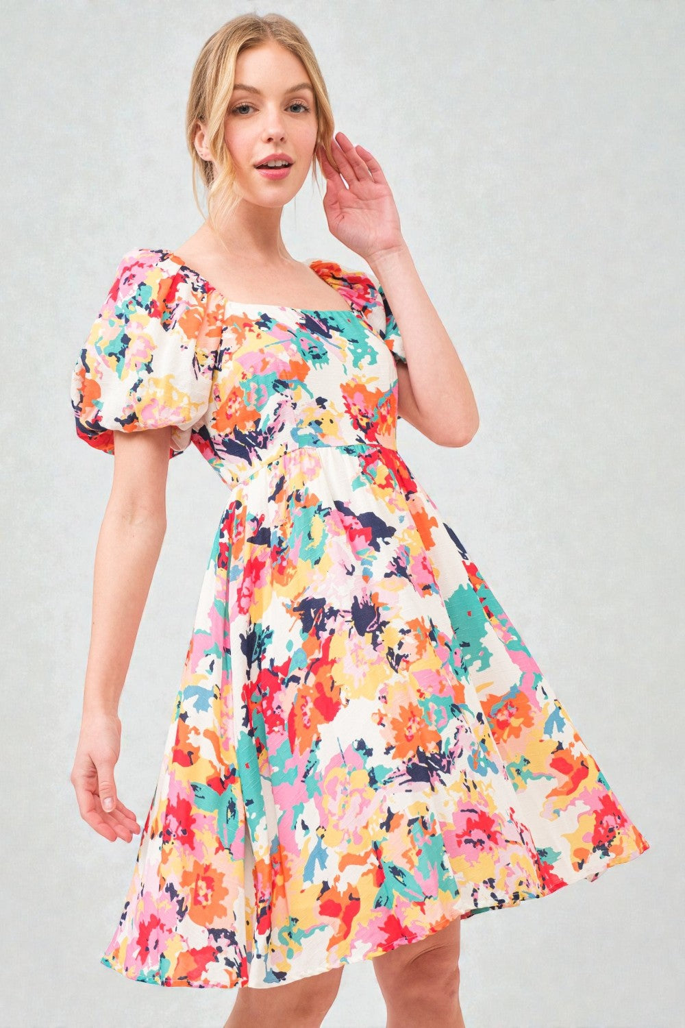 Woman wearing a colorful floral dress on a gray background