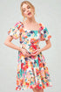 Woman wearing a colorful floral dress on a plain background