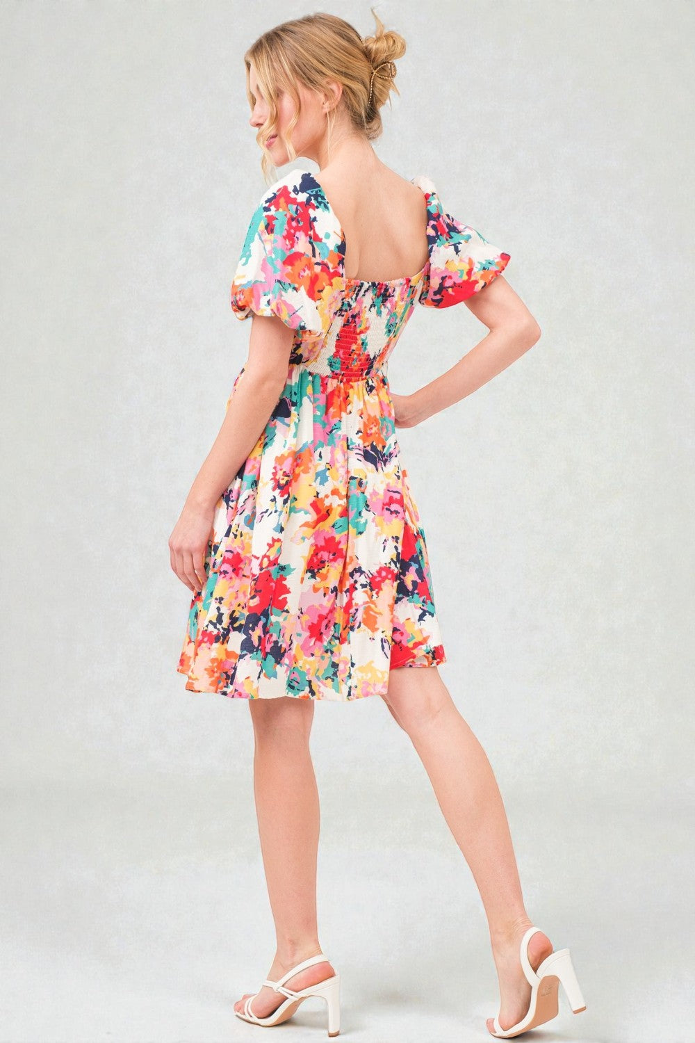 Woman wearing a colorful floral dress on a plain background