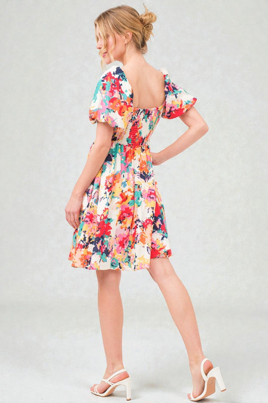 Woman wearing a colorful floral dress on a plain background