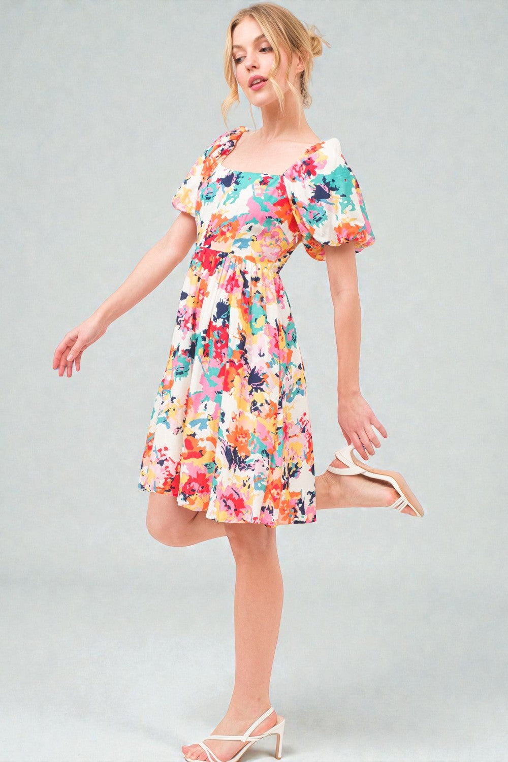 Woman wearing a colorful floral dress on a gray background