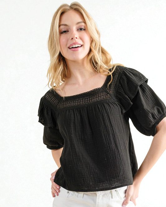 Woman wearing a black blouse with ruffled sleeves on a white background